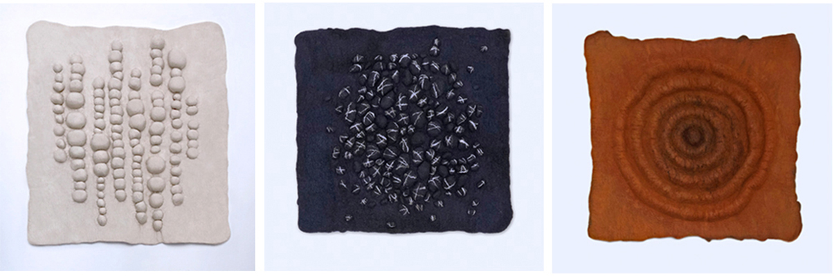 Three square textured fabric or felt art panels with bead-like, scattered stitch, and spiral patterns in cream, dark navy
